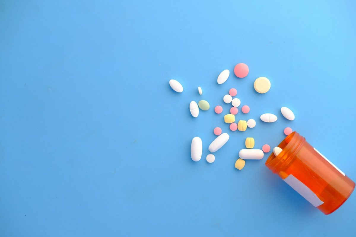 colorful pills spilling from orange bottle